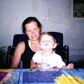 Happy woman smiling with laughing toddler indoors.