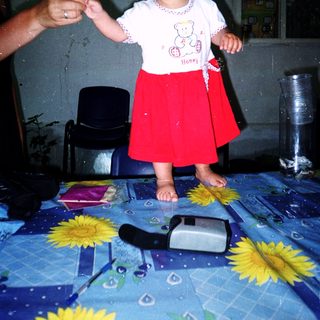 Toddler standing on table holding adult's hand.