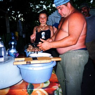 Man and child preparing food outdoors at night.