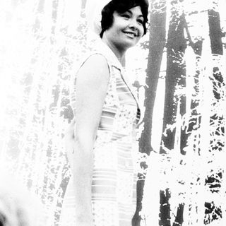 Woman smiling indoors near patterned wall.