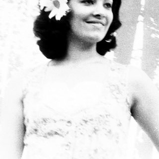 Woman in bridal gown with flower hairpiece indoors.