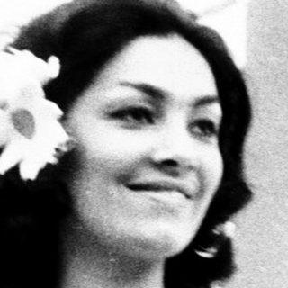 Woman in bridal gown with flower hairpiece indoors.
