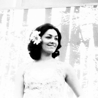 Woman in bridal gown with flower hairpiece indoors.