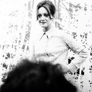 Woman in white blouse speaking at event.