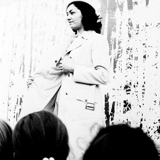 Woman in white lab coat speaking to audience.