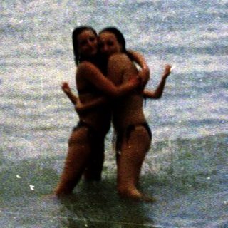 Two people hugging in shallow ocean water.