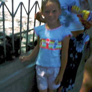 Girl smiling near water fountain on hot day.
