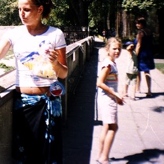Woman feeding bear at zoo enclosure.