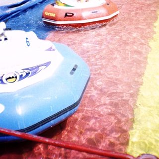 Person riding inflatable water bumper boat ride.