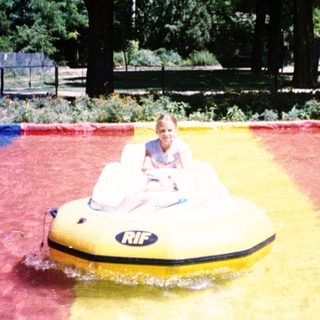 Two people riding bumper boats in water.