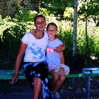 Two people sitting together outdoors in a shaded area.
