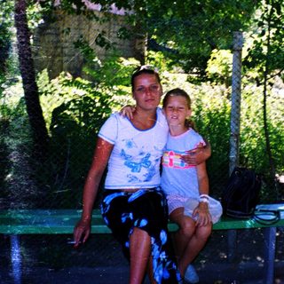 Two people sitting together outdoors in a shaded area.