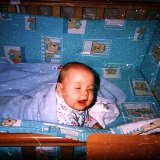 Sweet baby sleeping in a crib with stuffed animals.