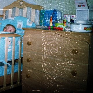 Baby sleeping in blue-themed crib with canopy.