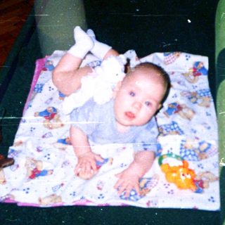 Baby lying on colorful blanket indoors.