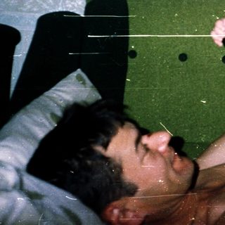 A man holding an infant above him in bed.