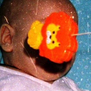 Baby in crib playing with hanging mobile.