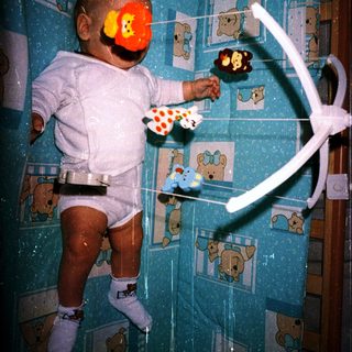 Baby in crib playing with hanging mobile.
