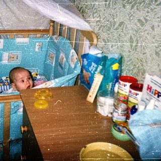 Baby in blue-themed crib with mosquito net.