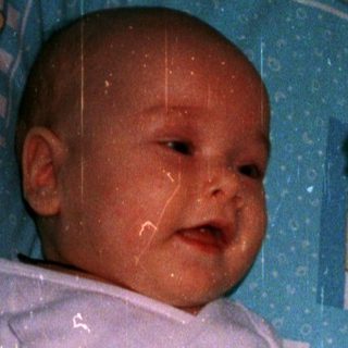 Baby in crib playing with hanging toys.
