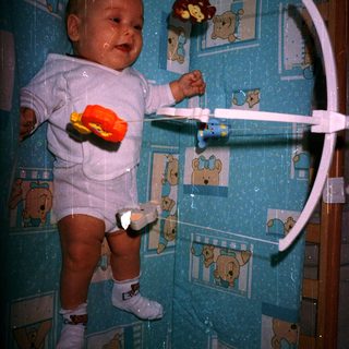 Baby in crib playing with hanging toys.