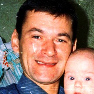 A man holding a baby in a celebratory setting.