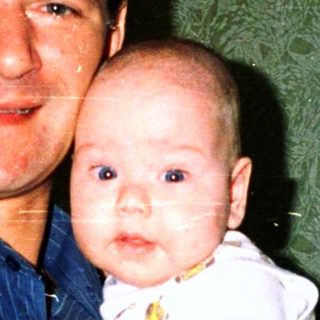 A man holding a baby in a celebratory setting.