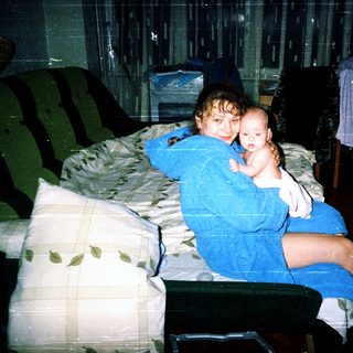 Two siblings sitting together on a bed.