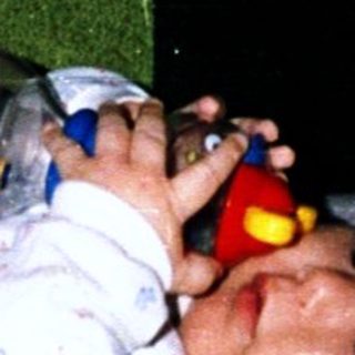 Baby sleeping peacefully with toy in hand.