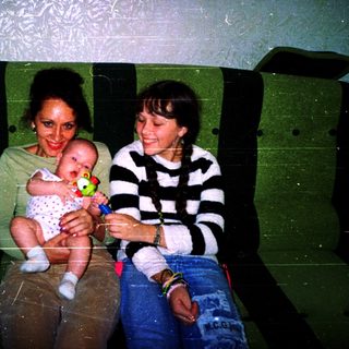 Two women sitting together holding a baby.