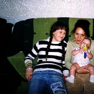 Three people sitting on a green couch indoors.