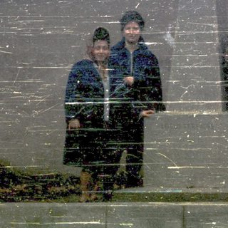 Four people posing in winter attire near reflective surface.