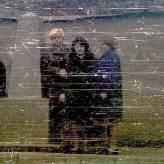 Reflection of people in rainy window.