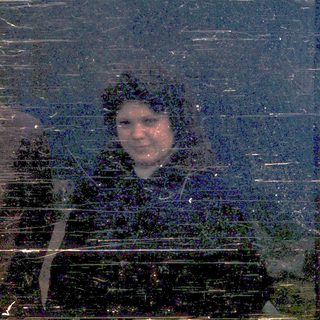 Three people smiling in a bus window during snowfall.