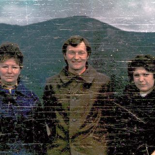 Three people posing outdoors in winter attire.