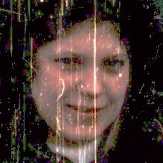 Person smiling in heavy rain outdoors.