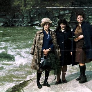 Three women posing near a rocky waterfall.