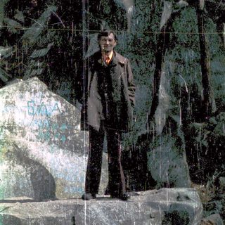 Man standing outdoors in front of reflective glass mural.