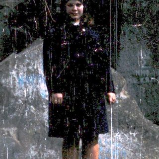 Girl standing in reflective glass with dark background.