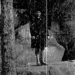 Person standing in rain under reflective glass.