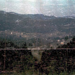 Mountainous landscape with valley and scattered buildings.