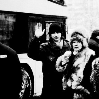 Cold winter scene with armed officers detaining a person.