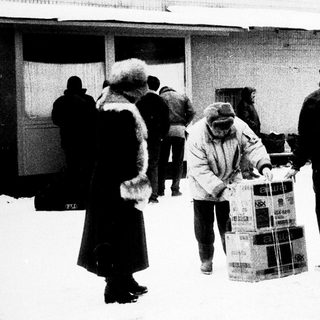 People carrying large boxes in snowy outdoor setting.