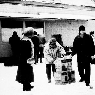 People carrying large boxes in snowy outdoor setting.