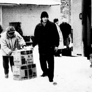 People carrying large boxes in snowy outdoor setting.