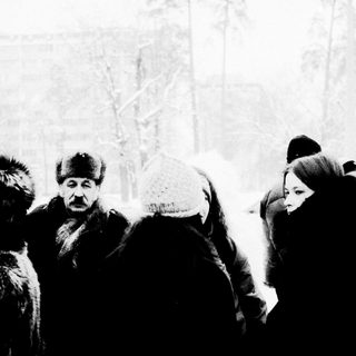 People bundled in winter clothing in snowy outdoor setting.