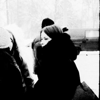 People bundled in winter clothing in snowy outdoor setting.