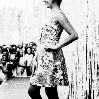 Woman in floral dress posing on elevated walkway.