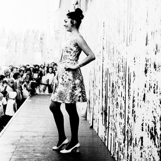 Woman in floral dress posing on elevated walkway.