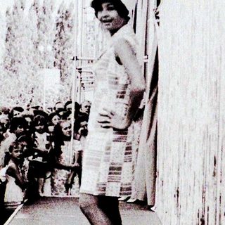 Person standing alone on a platform near a crowd.